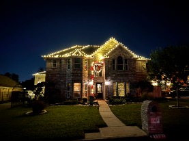 Two-story brick home with warm white rooflines and a lit entry